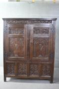 A 17th century country oak twin door hall cupboard with carved frieze and panels raised on stile