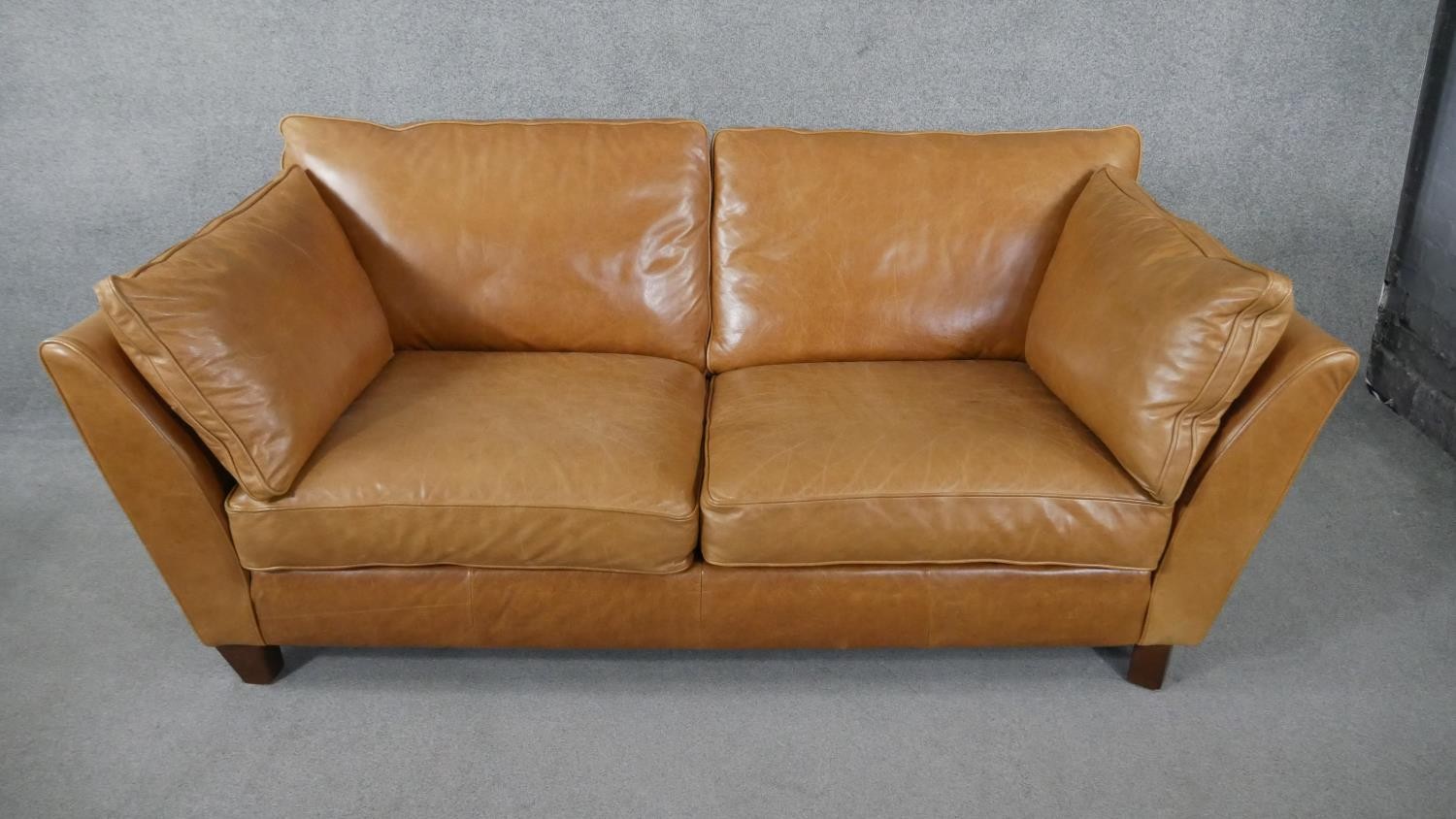 An Art Deco style two seater sofa in light tan leather upholstery. H.84 W.179 D.97cm