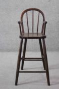 A vintage hooped back Windsor style child's high chair on shaped circular section stretchered