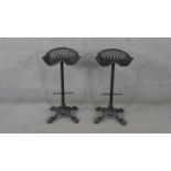 A pair of vintage cast iron tractor seat high stools on quadruped foliate supports.