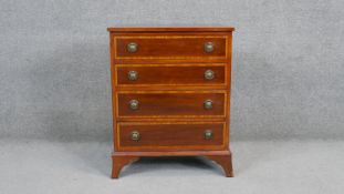 A small Georgian style mahogany chest of drawers with satinwood crossbanding on swept bracket