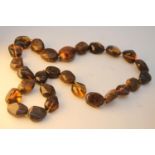 A large knotted statement necklace of a string of twenty seven polished amber beads. Weight. 101g.