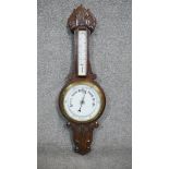 A late 19th century carved oak banjo barometer with white enamel dials and foliate design. H.84 W.