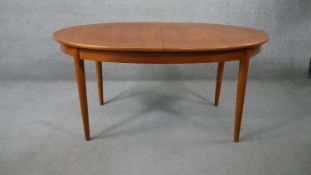 A mid century vintage teak dining table fitted with integral fold out central extension leaf. H.