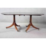 A Georgian style figured mahogany dining table with extra leaf on swept tripod pedestal supports.