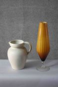 A large Art Pottery white glazed jug along with a large ridged amber Art Glass pedestal vase. H.46
