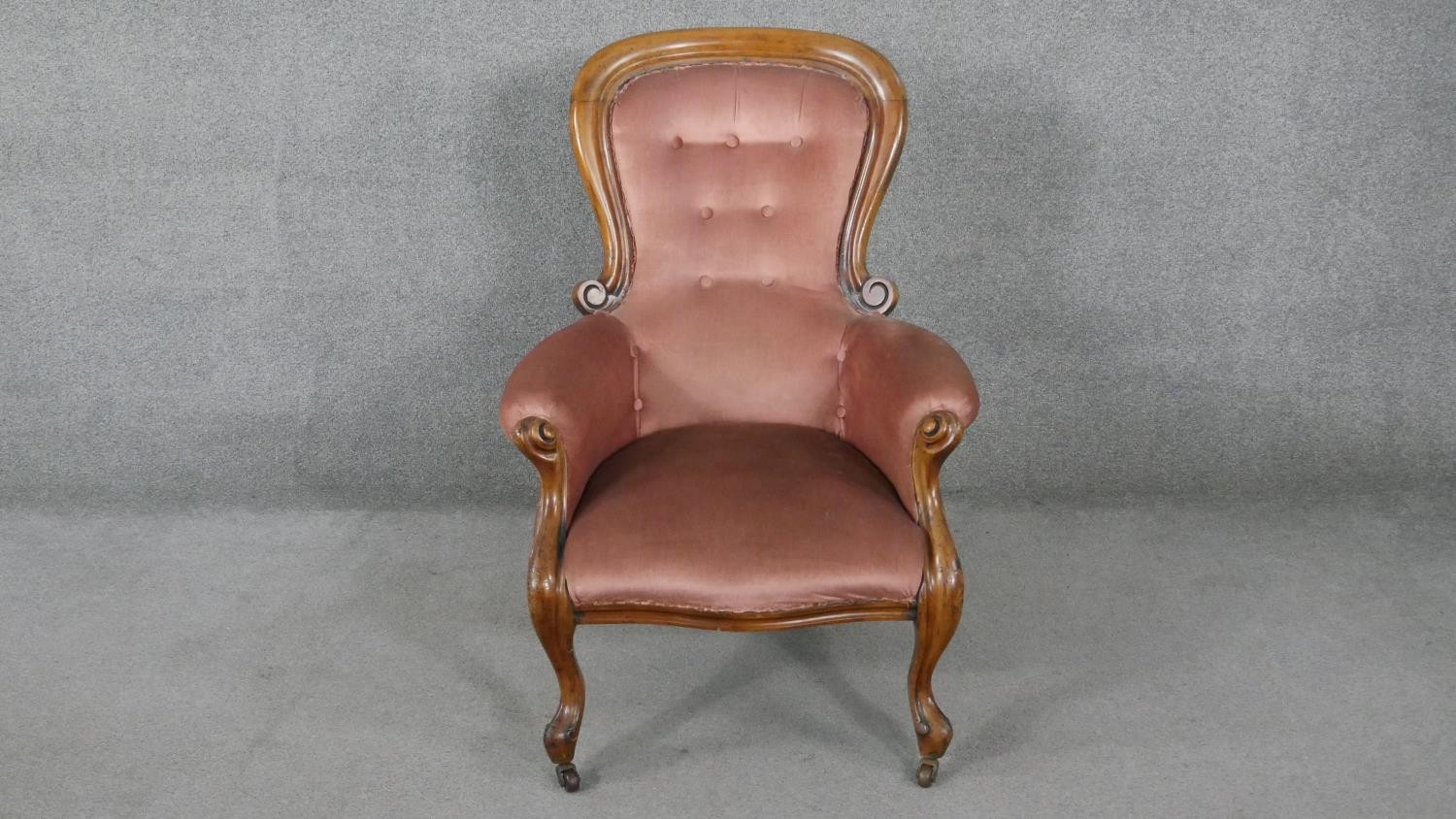 A 19th century walnut framed armchair in buttoned velour upholstery on cabriole supports.