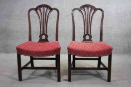 A pair of Georgian mahogany dining chairs with pierced and carved splats above shaped stuffover