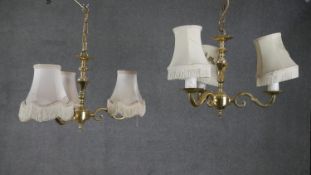 A pair of vintage brass three branch scrolling design candelabras with cream silk shades with tassel