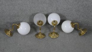 Four vintage brass wall mounted lights with globe shades. Three with opaque milk glass shades and