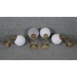 Four vintage brass wall mounted lights with globe shades. Three with opaque milk glass shades and