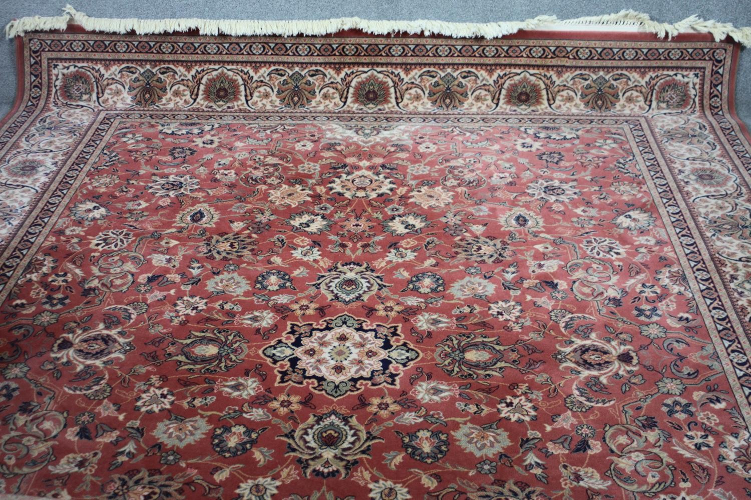 A Keshan motif woollen carpet with central medallion and trailing foliate pattern on a burgundy