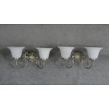 A pair of brushed brass and glass two branch wall lights. Each with two bell shaped frosted milk