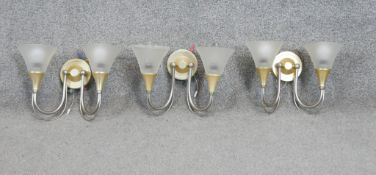 Three two branch silver and gold tone metal wall lights with frosted conical shades. H.24 W.30 CM