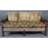 A mid century carved walnut three seater bergere sofa with double caned sides in cut floral