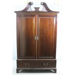A 19th century mahogany wardrobe with pierced arched swan neck pediment above fielded panel doors