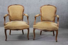 A pair of Louis XV style carved walnut framed armchairs in velour upholstery on cabriole supports.