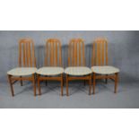 A set of four mid century vintage teak dining chairs on shaped circular section stretchered