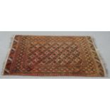 An Afghan rug with repeating stylised geometric motifs on a terracotta ground within multiple