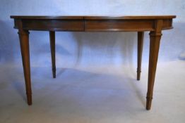 A walnut extending dining table with three extra leaves raised on square tapering supports. H.73 W.
