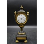 A 19th century French empire ormolu and bronze urn shaped mantel clock, with a white enamel dial and