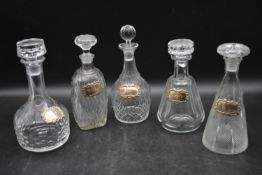 Five miscellaneous Victorian cut crystal decanters with silver drinks labels. Hallmarked. H.34cm