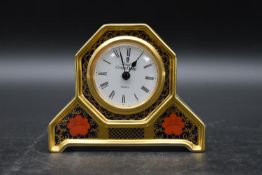 An early 20th century Royal Crown Derby clock with white enamel dial and stylised with gilded border