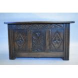 A mid century oak Jacobean style coffer with carved panels on block supports. H.47 W.84 D.45cm