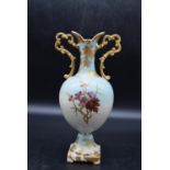 A 19th century twin handled urn vase with gilded detailing and hand painted floral and bird