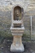 A weathered cast reconstituted stone lion mask alcove fountain on pedestal base. H.163 W.51 D.55cm