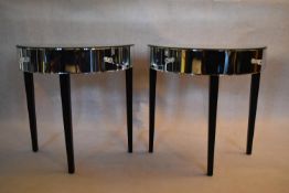 A pair of mirrored demi lune console tables fitted with frieze drawers on square tapering ebonised