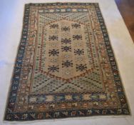 An Eastern carpet with repeating floral motifs on a sand ground within foliate spandrels and