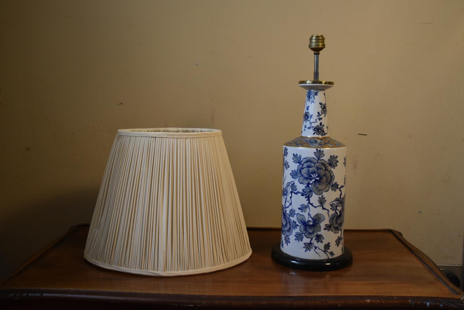 A contemporary blue and white table lamp, with floral decoration and a cream pleated shade. H.50