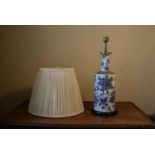 A contemporary blue and white table lamp, with floral decoration and a cream pleated shade. H.50