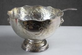 A hand chased floral design silver plate punch bowl and ladle. The pedestal bowl with twin lion head