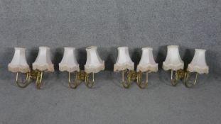 a set of four brass twin branch scrolling design wall lights with cream silk shades and tassel