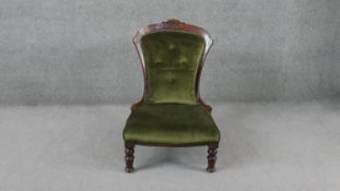 A late 19th century carved mahogany framed nursing chair on turned tapering supports.