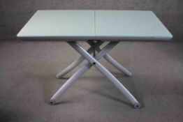 A contemporary metal framed glass top table with height adjustable action retailed by Heal's. H.74