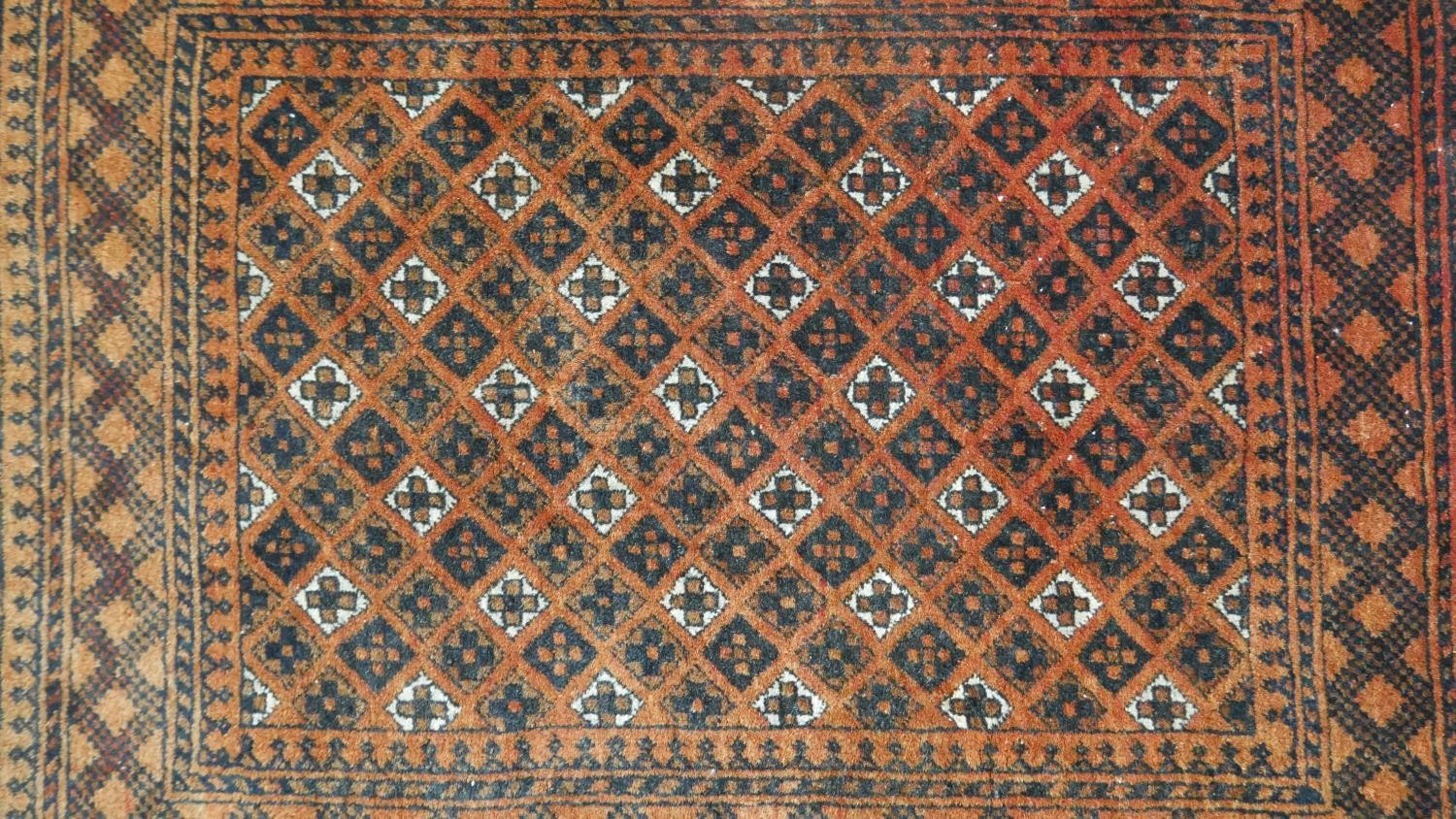 An Afghan rug with repeating stylised geometric motifs on a terracotta ground within multiple - Image 2 of 5