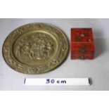 A repousse brass decorative plate with tavern scene and horn of plenty motifs along with a red