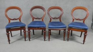 A set of four Victorian carved and shaped back mahogany dining chairs on turned tapering supports.