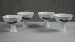 Four Chinese 19th century Kangxi style porcelain stemmed bowls decorated with oxblood glaze fish.