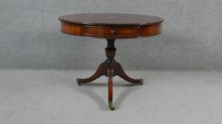 A Georgian style mahogany library drum table with inset gilt tooled leather top on swept tripod
