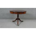 A Georgian style mahogany library drum table with inset gilt tooled leather top on swept tripod