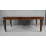 A C.1900 mahogany extending dining table with two extra leaves on husk carved square tapering