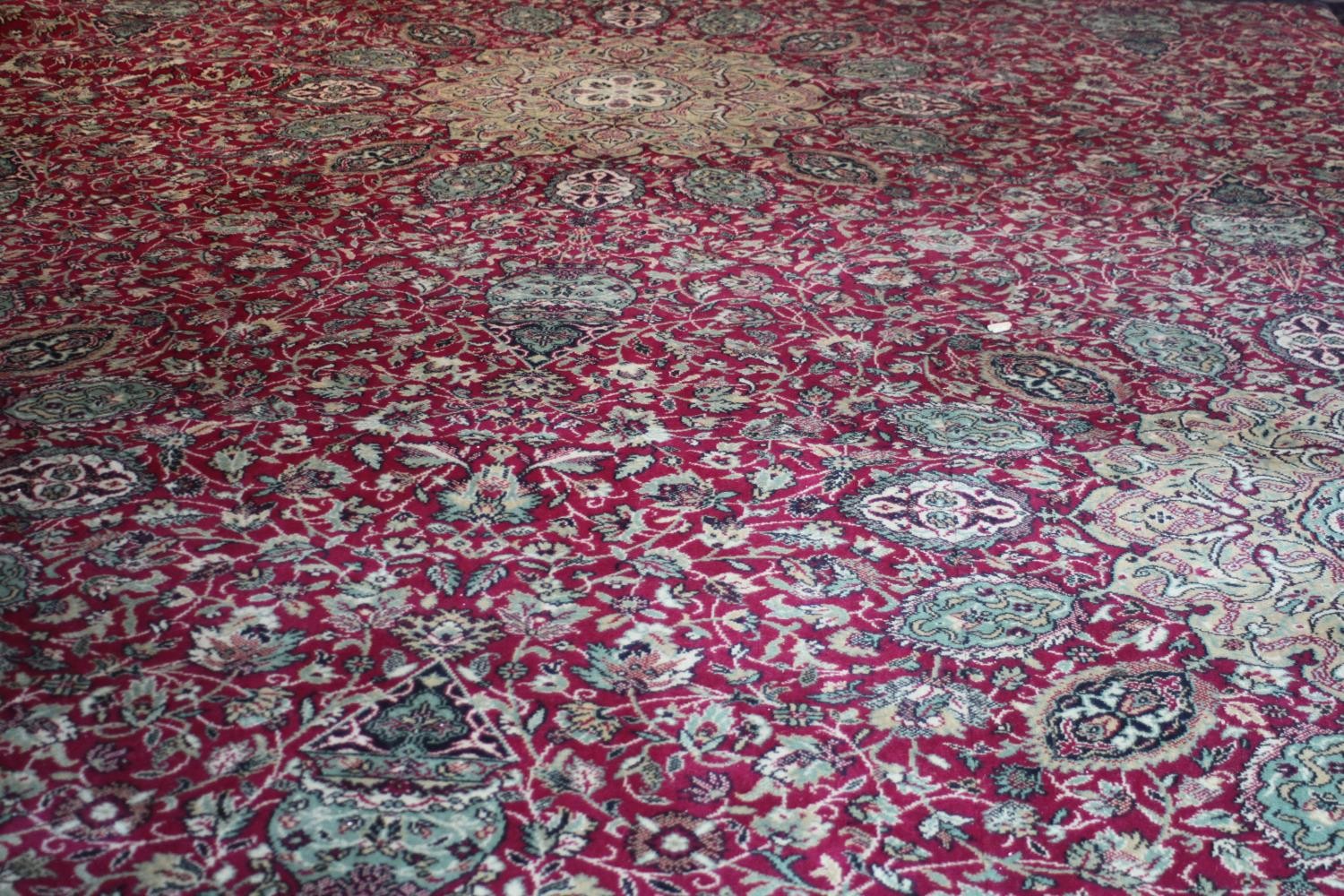 A large Wilton carpet with repeating floral medallions and trailing foliate decoration on a burgundy - Image 5 of 11