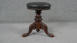 A mid Victorian carved mahogany piano stool with revolving rise and fall action on tripod cabriole