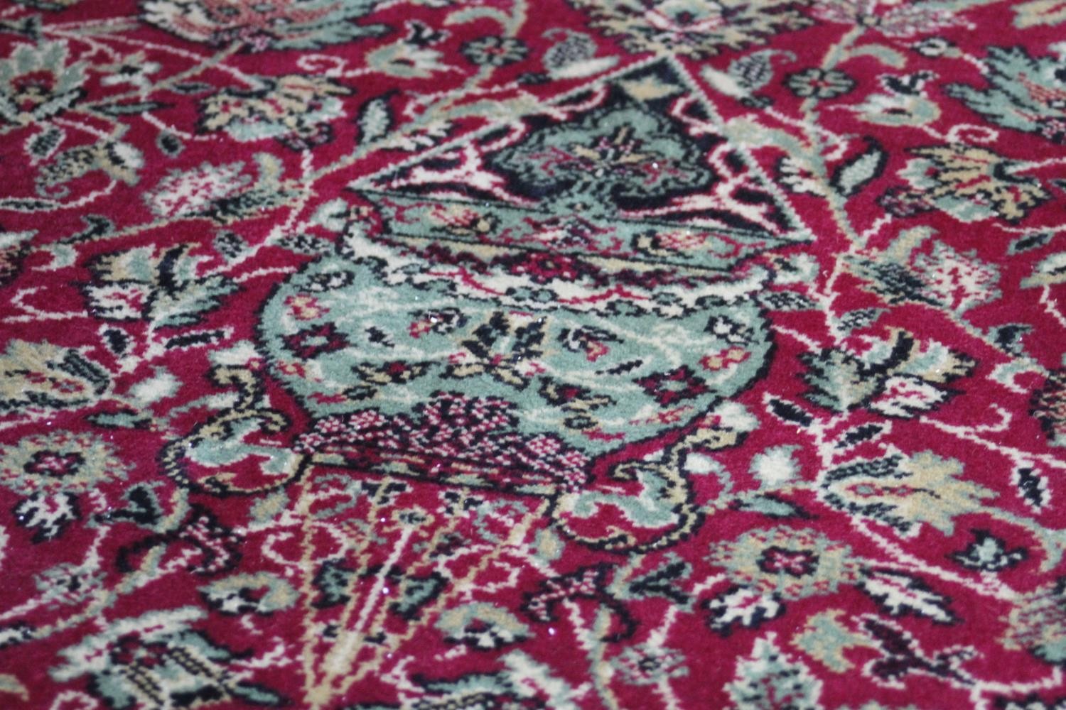 A large Wilton carpet with repeating floral medallions and trailing foliate decoration on a burgundy - Image 9 of 11