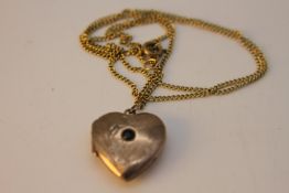 A Russian silver gilt heart locket with engraved foliate design and set to centre with a blue