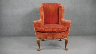 An early Georgian style wing back armchair in cut striped velour upholstery raised on four walnut